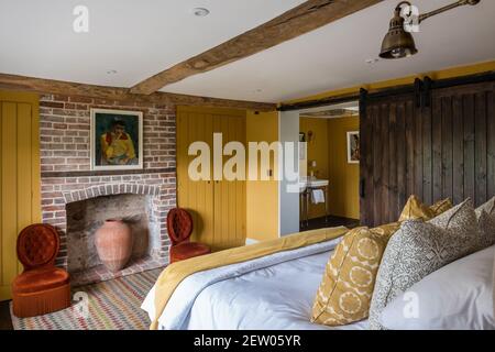 Porte coulissante par Tom Dunn dans la chambre avec un accent jaune dans la rénovation de ferme hors-grille. Banque D'Images