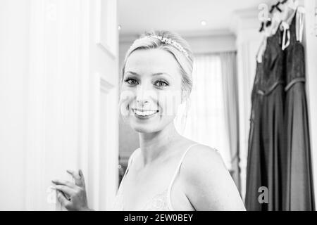 Mariée souriante le jour de son mariage. Robes de demoiselle d'honneur suspendues à l'arrière-plan Banque D'Images