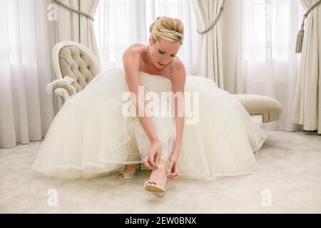 La mariée s'assoit sur une chaise longue dans le cadre d'un déambulage de costume de mariée sa lanière de chaussure Banque D'Images