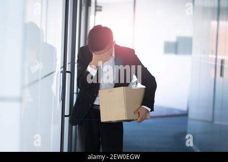 Homme d'affaires tiré portant une boîte d'objets personnels Banque D'Images