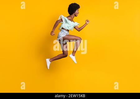 Photo de profil latéral pleine longueur de la taille du corps de saut haut femme courir vente rapide criant isolé sur couleur jaune vif arrière-plan Banque D'Images