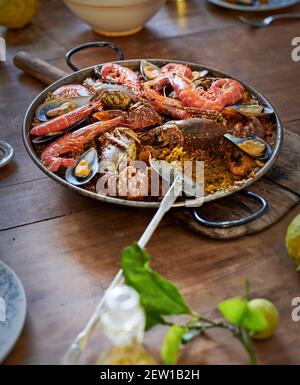 Délicieux plat de paella de fruits de mer avec riz et crevettes servis dessus assiette sur table en bois au restaurant Banque D'Images