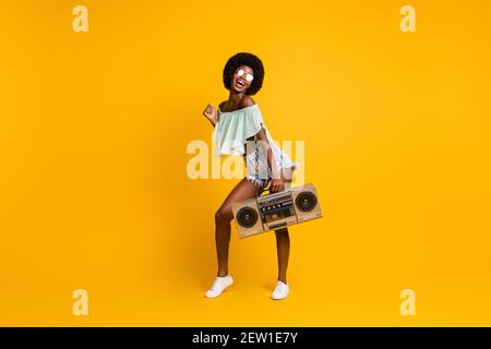 Pleine longueur photo de corps de la cassette fille à la peau noire enregistreur pour écouter de la musique et profiter de la fête, isolé sur une couleur jaune vif arrière-plan Banque D'Images