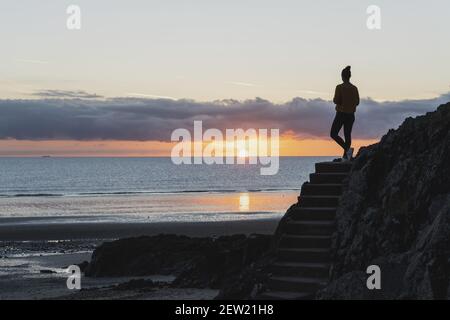 France, Côtes d'Armor, Plérin, jeune femme marchant à l'aube le long de la plage des rosaires Banque D'Images