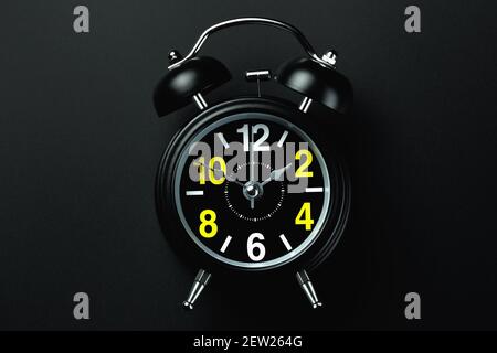 Un réveil noir élégant avec des chiffres jaunes et blancs se dresse sur un fond sombre. Vide pour le concepteur Banque D'Images