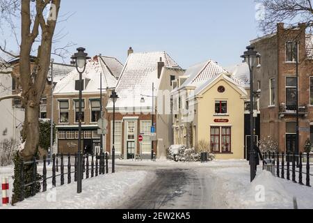 ZUTPHEN, PAYS-BAS - 10 février 2021 : pont couvert de neige menant à des façades historiques colorées du centre-ville médiéval de la ville hollandaise hanséatique Banque D'Images