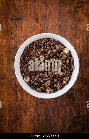 Céréales au chocolat pour le petit déjeuner. Granola du matin dans un bol sur une table en bois. Vue de dessus. Banque D'Images