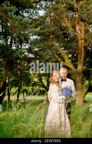 Mariée et marié avec un bouquet d'hortensias dans un pinède Banque D'Images