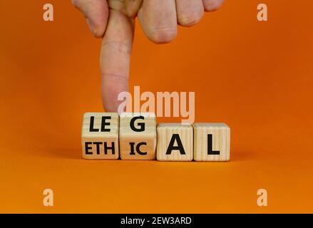 Symbole éthique ou juridique. Homme d'affaires transforme des cubes en bois et transforme le mot « éthique » en « juridique » sur une belle table orange, fond orange. Busi Banque D'Images