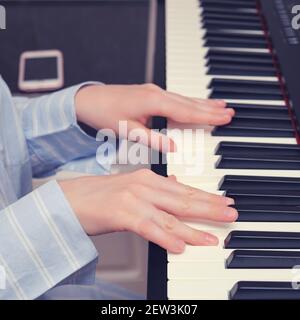 La musicienne joue du synthétiseur dans la cuisine maison, les mains en gros plan Banque D'Images