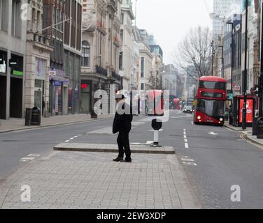 Oxford Street Londres, pendant le coronavirus Covid-19 confinement pandémique un homme seul traverse une rue exceptionnellement calme Oxford Street Banque D'Images