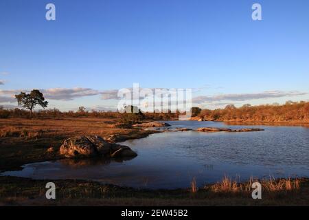 Illuminé par les derniers rayons du soleil, une rivière sud-africaine coule paisiblement dans une soirée de juillet. Banque D'Images