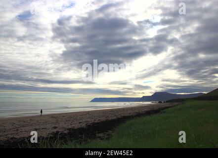 Silhouette d'une femme marchant sur une plage islandaise sous Des nuages impressionnants le soir de juillet (fjords du nord-ouest) Banque D'Images