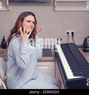 Une pianiste féminine en colère dans une nuit bleue lui a violemment soulevé ses mains, des problèmes de jouer du piano Banque D'Images