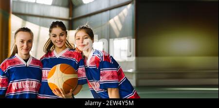 Bannière - format long. Groupe de trois filles de sport, amis internationaux dans l'équipe sportswear posant à la caméra. Membres de basket-ball féminin Banque D'Images