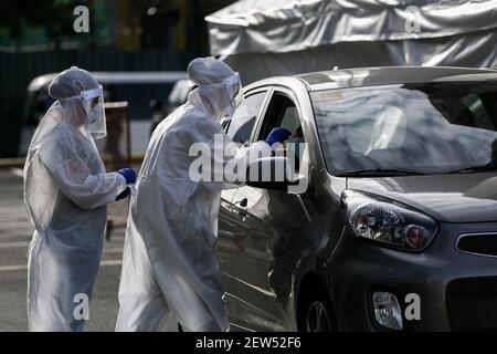 Les travailleurs médicaux portant des combinaisons de protection effectuent un test de détection du coronavirus au volant pendant la quarantaine communautaire renforcée de la COVID-19 à Taguig, dans la région métropolitaine de Manille, aux Philippines. Banque D'Images