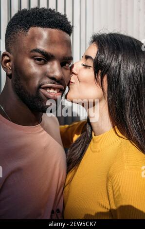 Belle femme se déplace pour embrasser le visage d'un frais homme noir regardant la caméra Banque D'Images