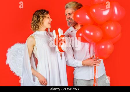Couple charmant à la Saint Valentin. Ange Cupidon avec des cadeaux et des ballons. Couple en Saint-Valentin. Banque D'Images