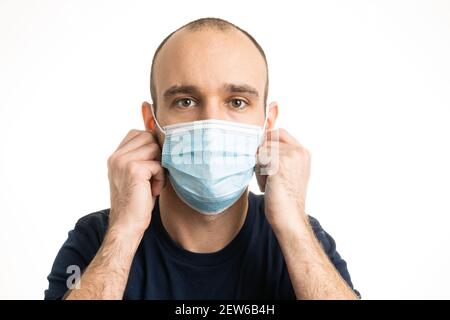 Un homme blanc de race blanche portant un t-shirt bleu et portant un masque chirurgical bleu. Banque D'Images