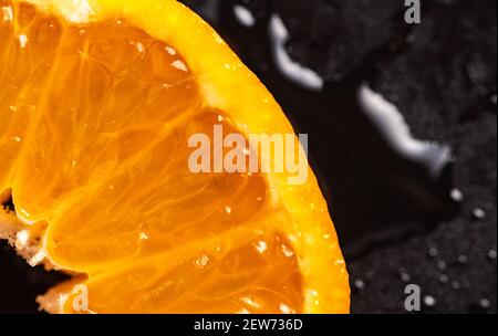 Coupe Mandarin, gros plan détaillé sur fond noir couvert de gouttes d'eau. Banque D'Images