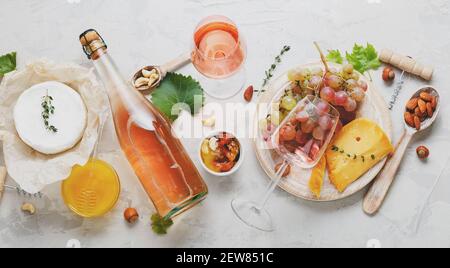 Délicieux repas vins divers en-cas servis à bord. Vin rose fromage vieilli Camembert noix miel raisin rouge verres de vin. Longue pose à plat Banque D'Images