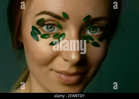 Gros plan du visage de la jeune femme avec des feuilles de buis. Bannière de modèle de spa et de bien-être pour le design. Publicité de produits cosmétiques Banque D'Images