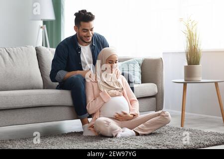Un mari arabe attentionné fait un massage des épaules pour une femme musulmane enceinte à la maison Banque D'Images