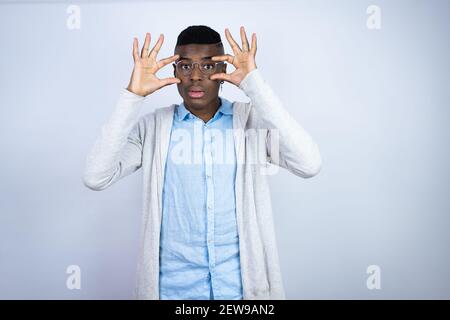 Jeune homme afro-américain élégant portant des vêtements décontractés essayant d'ouvrir les yeux avec les doigts, endormi et fatigué pour la fatigue matinale Banque D'Images