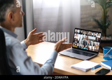 Un homme adulte prospère utilise un ordinateur portable pour la communication vidéo avec ses partenaires commerciaux. Un responsable ou pdg est assis à son bureau, parlant sur un appel vidéo avec des collègues, les employés prospères sont sur le Banque D'Images