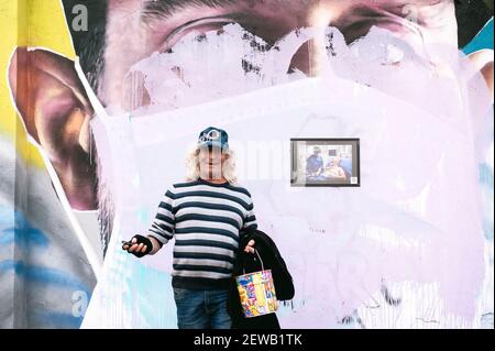 Milan, Italie. 26 février 2021. Un homme âgé qui pose à proximité d'un portrait annulé portant un masque facial.des portraits dédiés aux travailleurs de la santé de l'hôpital Luigi Sacco et aux proches des victimes de Covid-19, ont été représentés par l'artiste Cosimo Cheone, Et les associations locales, avec la coopération de la municipalité locale, en juillet 2020, dans le quartier de Quarto Oggiaro à Milan. Les peintures murales ont été récemment détruites en novembre 2020 par des inconnus, offensant la mémoire de ceux qui avaient combattu Covid-19. Crédit: Valeria Ferraro/SOPA Images/ZUMA Wire/Alay Live News Banque D'Images