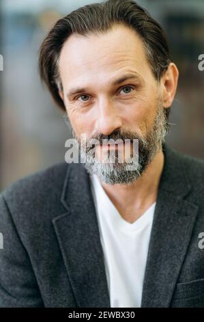 Portrait en gros plan d'un homme mature et influent en costume élégant. Homme d'affaires sérieux aux cheveux gris regardant directement la caméra, montrant la confiance en soi et le succès Banque D'Images