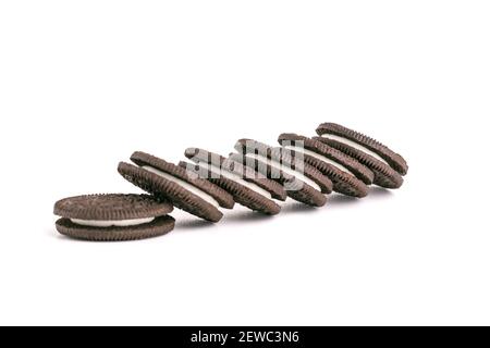 Biscuit fin noir chocolat avec garniture blanche, délicieux biscuit doux au lait éparpillé sur fond blanc Banque D'Images