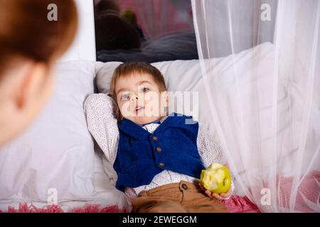 Maman vérifiant sur le fils malade qui se couche dans le lit. Mothercare pour un enfant malade. Banque D'Images