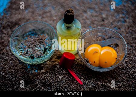 Masque de cheveux pour cheveux longs et sains composés de graines de cumin ou de zéera ou de jeera avec un peu de jaune d'œuf cru, de l'eau et un peu d'huile d'olive sur une couleur brune Banque D'Images