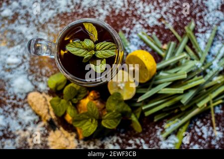 Injection de kada ayurvédique ou boisson d'immunité sur une surface brune composée de citronnelle, citron, feuilles de menthe, soonth ou poudre de gingembre séchée. Banque D'Images