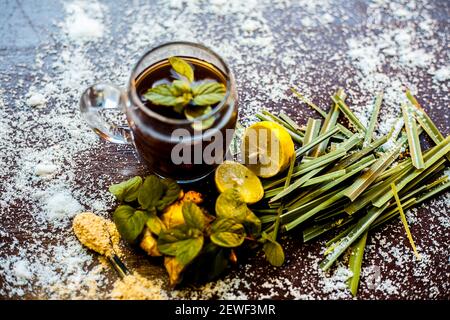 Injection de kada ayurvédique ou boisson d'immunité sur une surface brune composée de citronnelle, citron, feuilles de menthe, soonth ou poudre de gingembre séchée. Banque D'Images