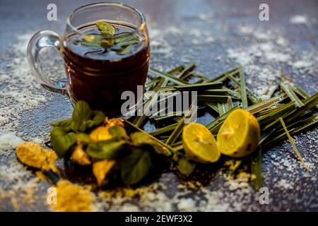 Injection de kada ayurvédique ou boisson d'immunité sur une surface brune composée de citronnelle, citron, feuilles de menthe, soonth ou poudre de gingembre séchée. Banque D'Images