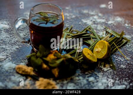 Injection de kada ayurvédique ou boisson d'immunité sur une surface brune composée de citronnelle, citron, feuilles de menthe, soonth ou poudre de gingembre séchée. Banque D'Images