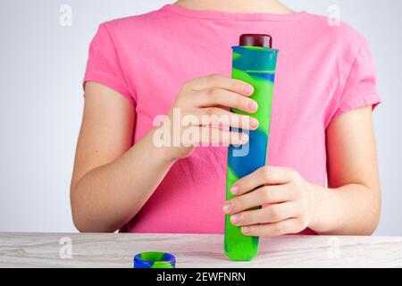 Une petite fille caise mignonne est de presser le sorbet de baie de popsicle surgelé hors de la moule coloré réutilisable de silicium. Un fond clair et aéré avec sel Banque D'Images