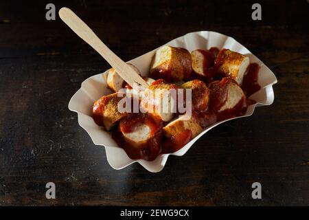 Grand angle de plat de viande de porc frite morceaux de saucisse avec salsa de tomate et poudre de curry à usage unique conteneur Banque D'Images