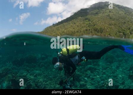 Plongeur avec caméra avec volcan Manado Tua en arrière-plan, site de plongée Bualo, Manado, Sulawesi, Indonésie Banque D'Images