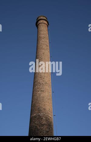 Un plan à faible angle d'une vieille grande cheminée de fabrique de céramique en briques sur fond bleu ciel Banque D'Images