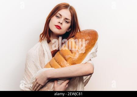 femme avec un maquillage brillant embrassant un grand pain dans elle mains Banque D'Images