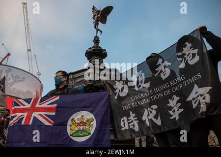 Londres, Royaume-Uni. 1er mars 2021. Les partisans de Hong Kong qui brandient et agrègent des drapeaux de protestation interdits ont lu « libérer Hong Kong, la Révolution de notre temps » et le drapeau colonial britannique à Piccadilly Circus, Londres, Royaume-Uni, le 01 mars 2021. Environ 50 partisans de Hong Kong se réunissent à Piccadilly Circus à Londres pour exprimer leur solidarité en soutenant les 47 activistes pro-démocratie de Hong Kong qui ont aidé et dirigé les élections primaires de l'année dernière sont accusés de conspiration pour subvertir le pouvoir de l'État en vertu de la loi sur la sécurité nationale lors de leur première audience judiciaire Hong Kong le 01 mars 2021, heure de Hong Kong. ( Banque D'Images