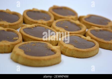 Délicieux et doux biscuits sablés en forme de pomme avec garniture de noix de chocolat marron située sur un fond blanc. Banque D'Images
