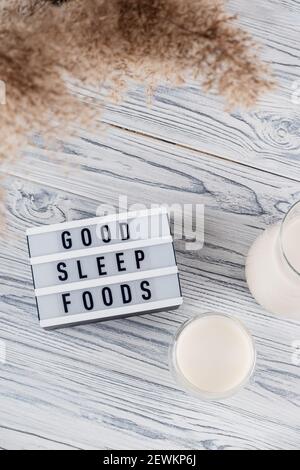 Lait malté de nuit pour un bon sommeil dans un pot et Verre à côté de l'inscription de bons aliments pour le sommeil Banque D'Images