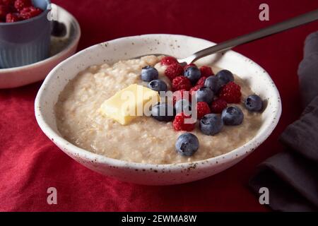 Porridge de flocons d'avoine avec myrtille et myrtille. Petit déjeuner dans un bol blanc et une cuillère avec des baies fraîches Banque D'Images