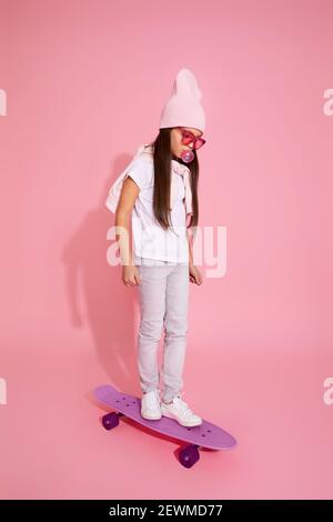 cool hipster petite fille avec chewing-gum sur le skateboard Banque D'Images