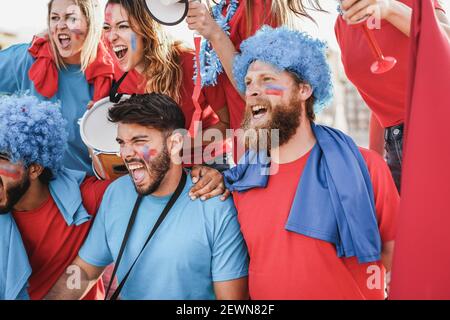 Les fans de sport fous jouant à la batterie et criant tout en soutenant leur Équipe - accent sur l'homme du centre Banque D'Images