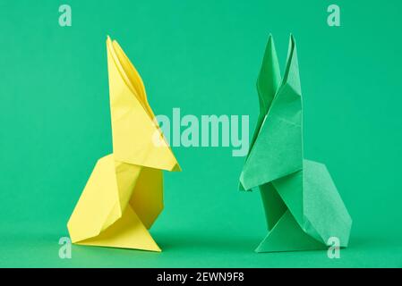 Deux lapins en papier d'origami Esater colorés sur fond vert. Concept de célébration de Pâques Banque D'Images